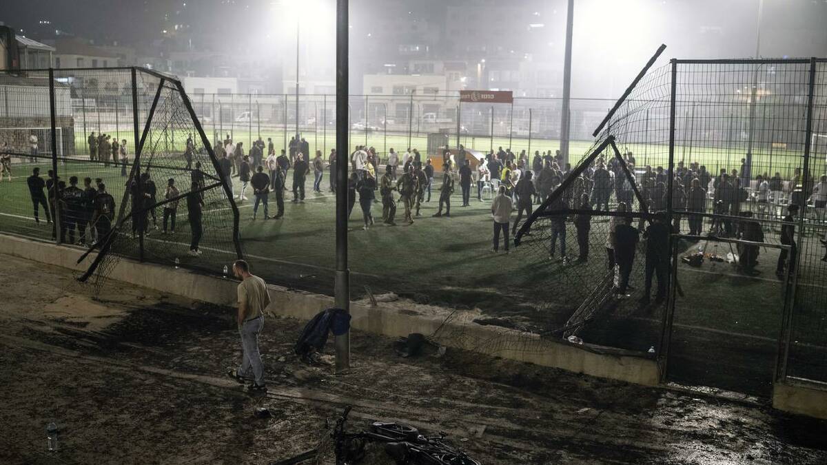 Residents stand at a football field that was hit by a rocket in the Druze town of Majdal Shams. (AP PHOTO)