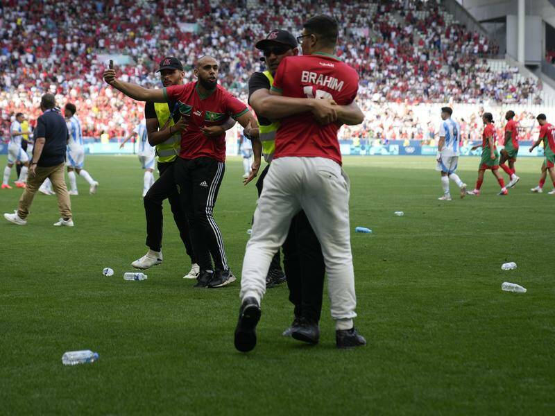 Stewards grapple with pitch invaders who force a  halt to Morocco's match with Argentina. Photo: AP PHOTO