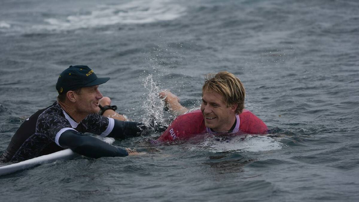 Ethan Ewing celebrates with coach Bede Dirbidge after winning his Olympics surfing heat. (AP PHOTO)