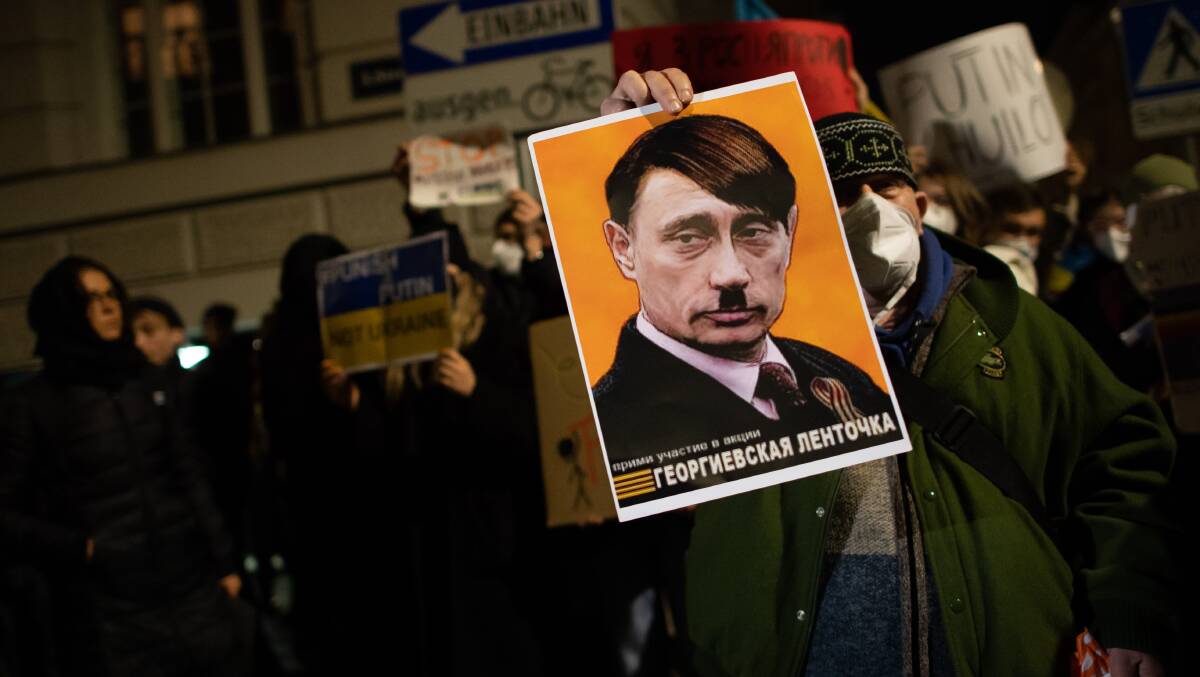 A demonstrator in Vienna holds up a sign depicting Russian President Vladimir Putin as Adolf Hitler. Picture: Getty Images