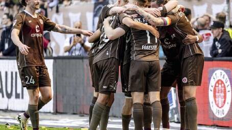 No.24 Connor Metcalfe joins Jackson Irvine (R) in the huddle after St Pauli's third sealing goal. (AP PHOTO)